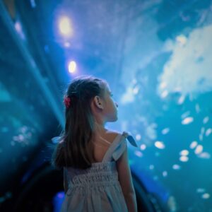 Girl looking up at fish in the ocean tunnel
