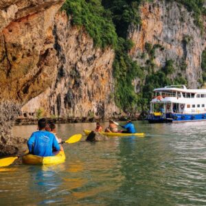 Guests kayaking with the tour boat behind them