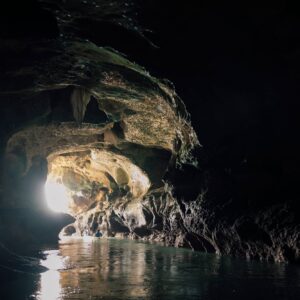 Kayak paddling out of a cave into a lagoon