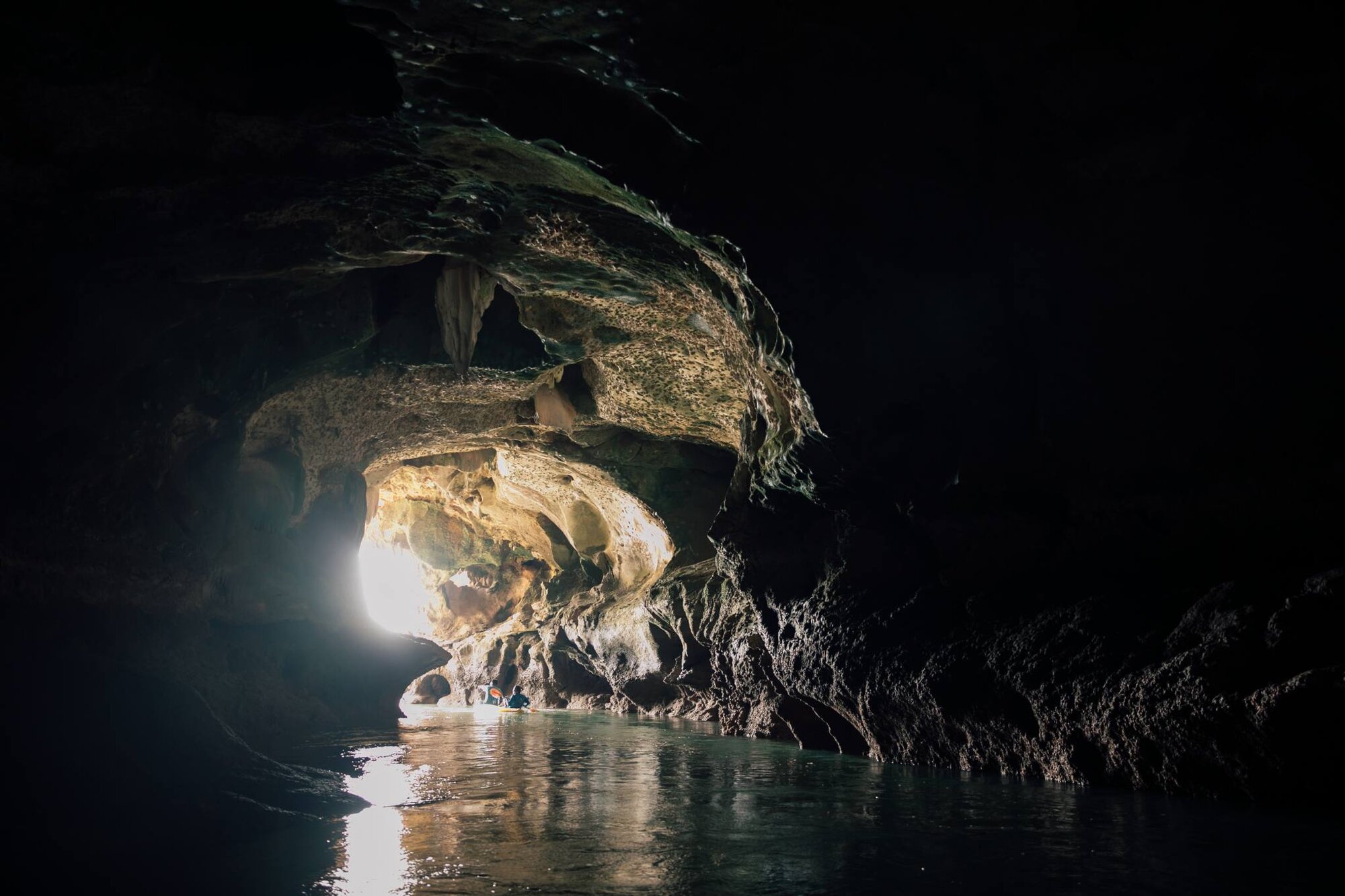 Kayak paddling out of a cave into a lagoon