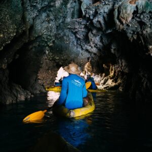Guide paddling a guest through a dark cave