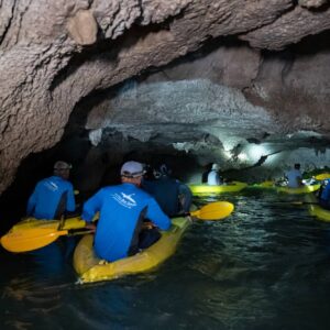 Kayaks entering a sea cave with headlamps
