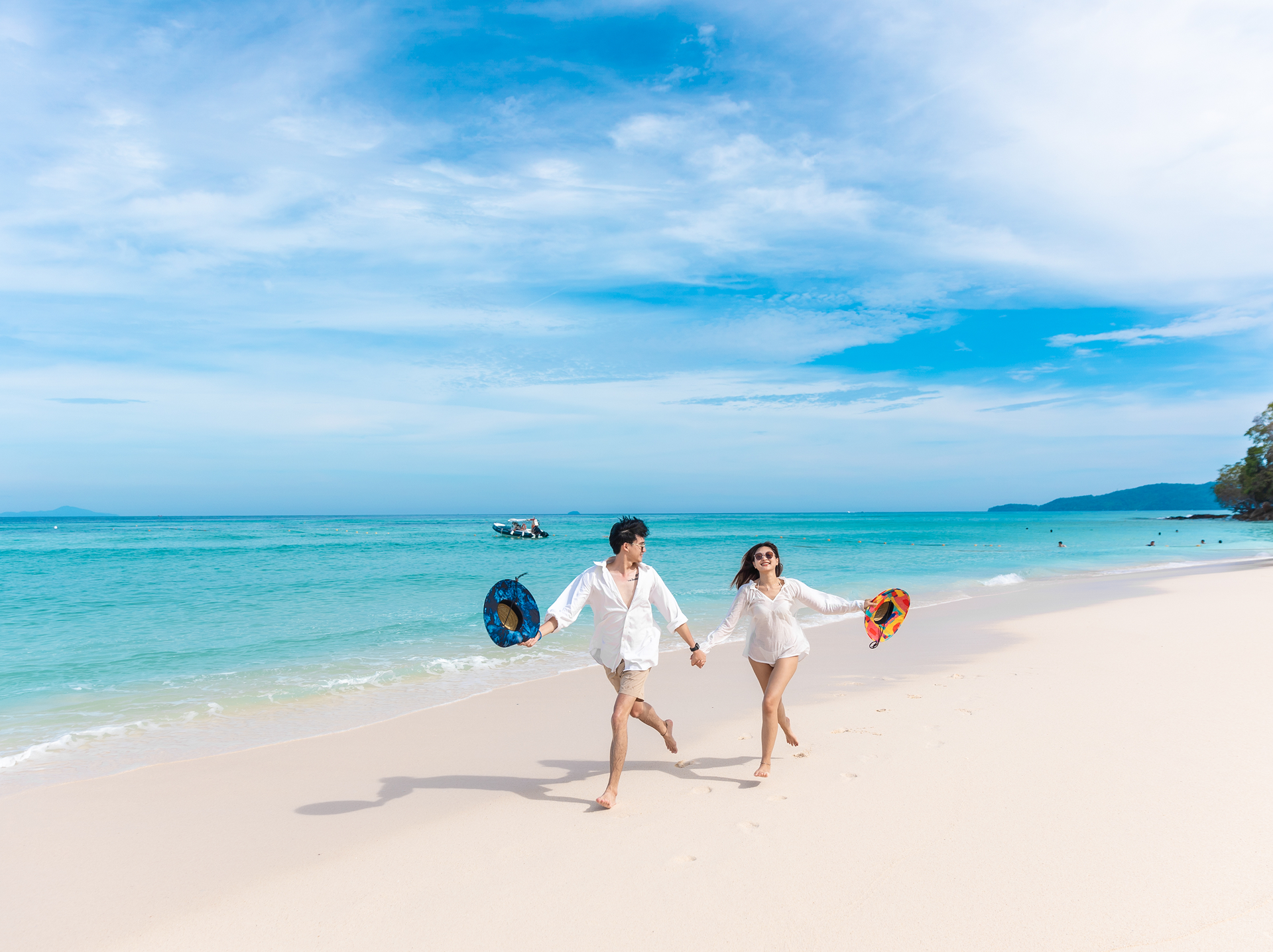 Couple walking hand in hand on a white sand beach in the Phi Phi Islands