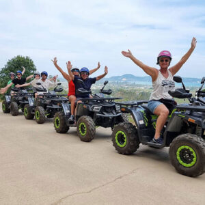 Riders cheering beside their ATVs at a sea-view point near Big Buddha
