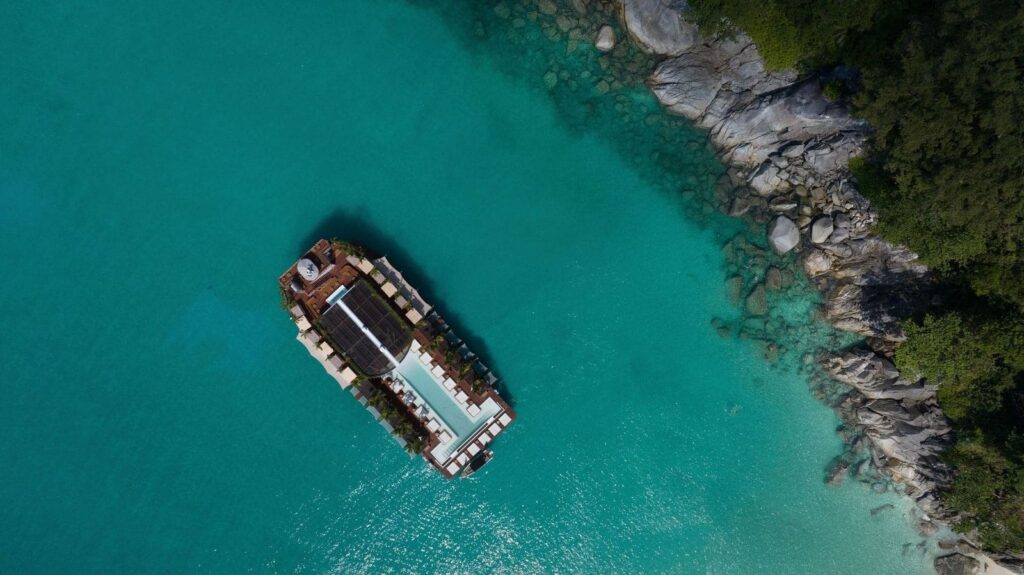 Aerial view of the floating beach club anchored off a rocky Phuket shore