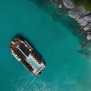 Aerial view of the floating beach club anchored off a rocky Phuket shore