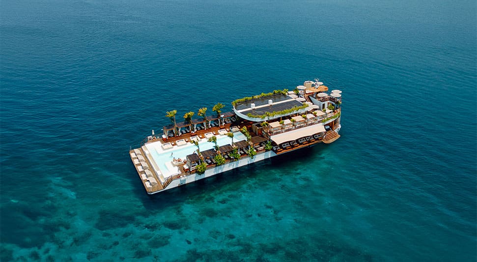 Floating beach club with pool and palm trees out at sea