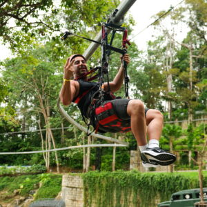 Rider on a roller zipline seat through the trees
