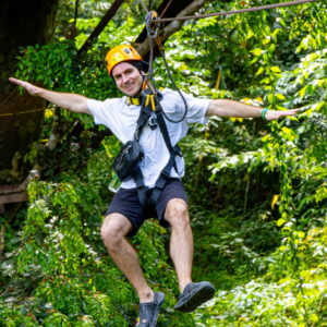 Zipline rider flying through the rainforest canopy in Phuket