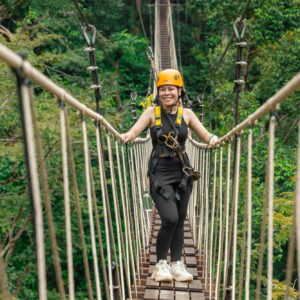 Guest crossing a rope sky bridge between treetop platforms