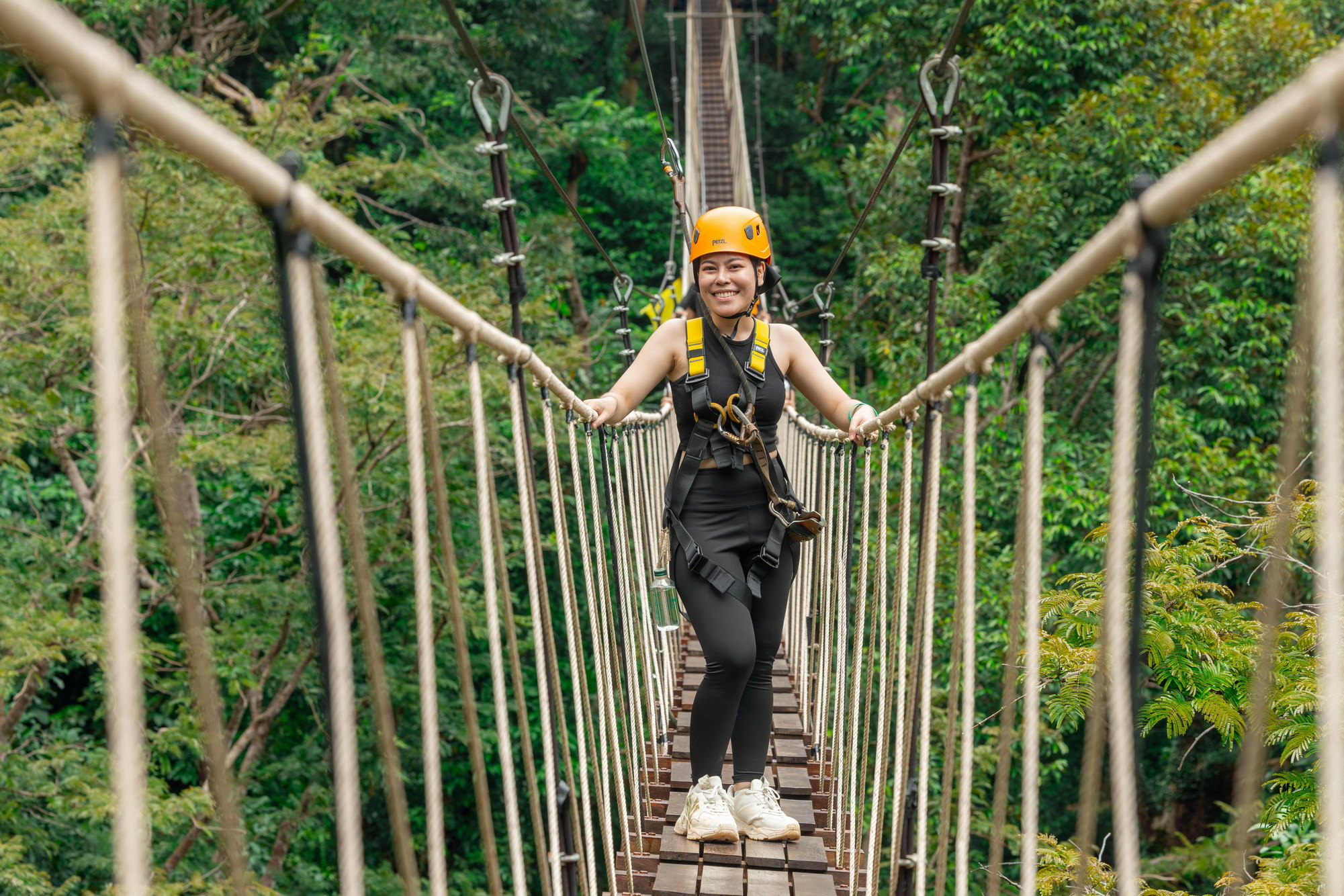 Guest crossing a rope sky bridge between treetop platforms