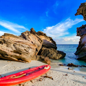 Rock formations and a kayak on a white sand beach