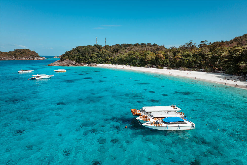 Speedboats anchored off a white beach in the Similan Islands