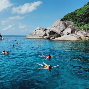 Snorkellers in clear water beside granite boulders in the Similan Islands