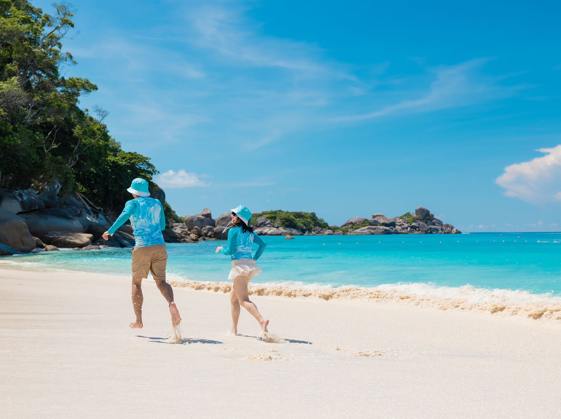 Two travellers running along a white sand beach in the Similan Islands